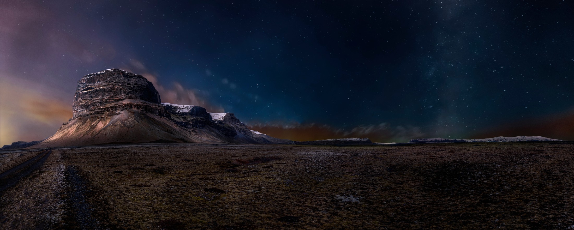 A dark mountain range beneath a star-filled night sky.